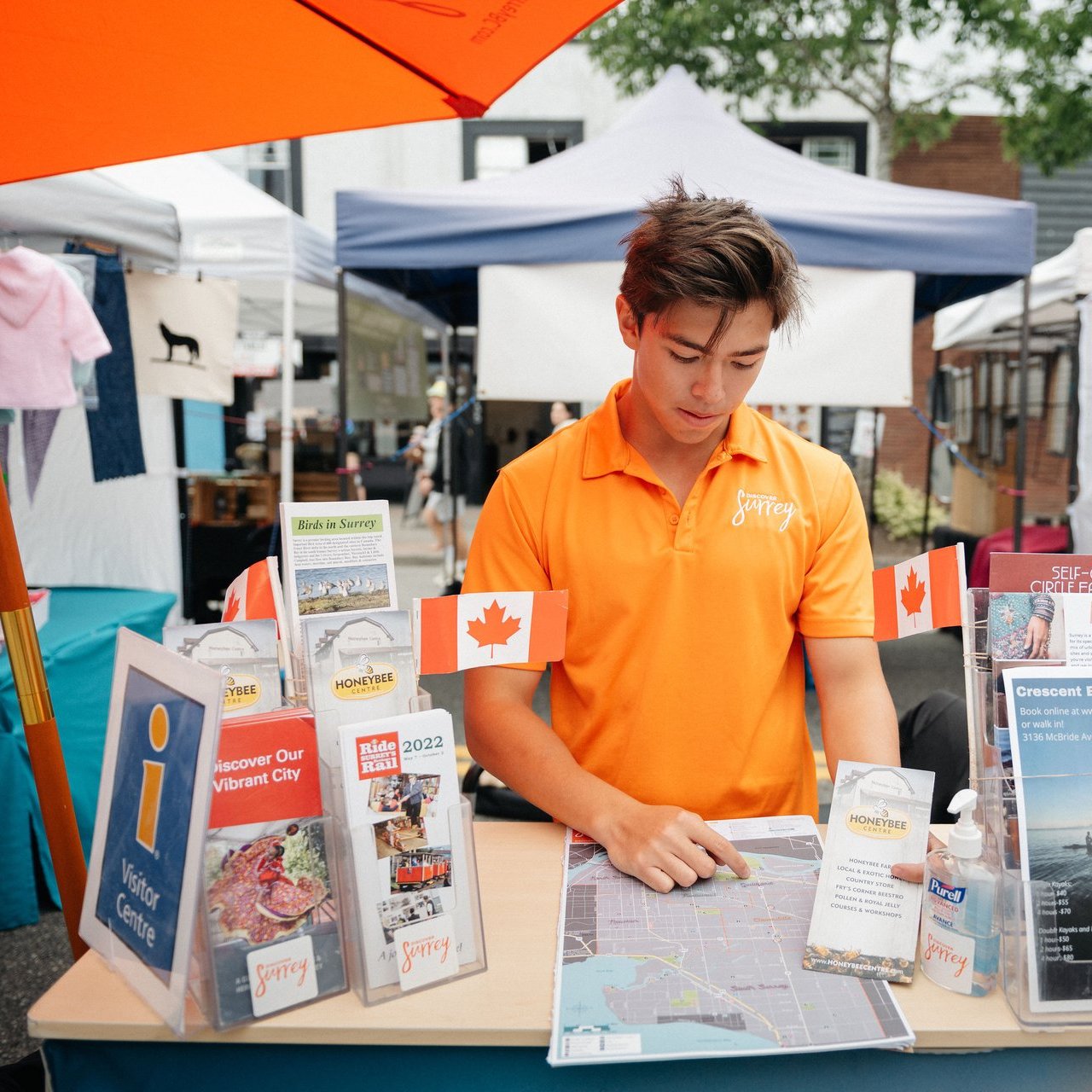 Visitor services rep shows location maps at the Cloverdale Market in Surrey BC Ian Harland DSC 3085